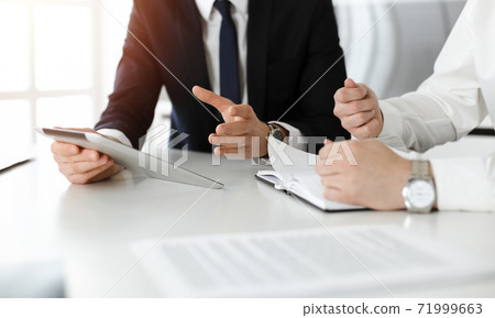Unknown business people using tablet computer in sunny office. Businessman is working with his colleague at the desk, close-up Unknown business people using tablet computer in sunny office. Businessman is working with his colleague at the desk, close-up 71999663