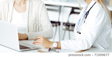 Unknown woman-doctor sitting and communicating with female patient. Physician checks medical history record and exam results, close-up. Healthcare concept Unknown woman-doctor sitting and communicating with female patient. Physician checks medical history record and exam results, close-up. Healthcare concept 71999677