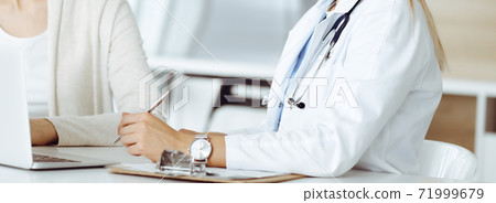 Unknown woman-doctor sitting and communicating with female patient. Physician checks medical history record and exam results, close-up. Healthcare concept Unknown woman-doctor sitting and communicating with female patient. Physician checks medical history record and exam results, close-up. Healthcare concept 71999679
