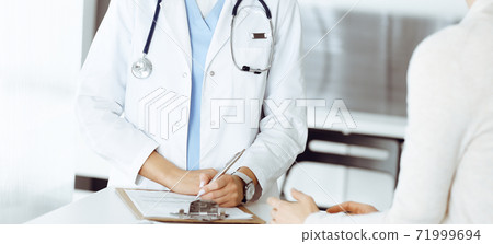 Unknown woman-doctor and patient in hospital. Blonde physician controls medication history records and exam results while using clipboard, close-up. Medicine concept Unknown woman-doctor and patient in hospital. Blonde physician controls medication history records and exam results while using clipboard, close-up. Medicine concept 71999694