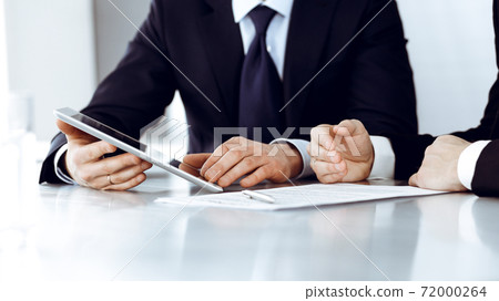 Business people using tablet computer while working together in modern office. Unknown businessman with colleague at workplace. Teamwork and partnership concept Business people using tablet computer while working together in modern office. Unknown businessman with colleague at workplace. Teamwork and partnership concept 72000264