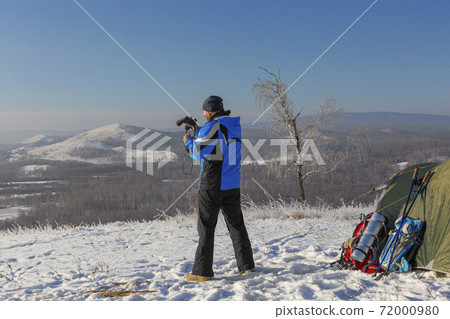 A man at the top of the mountain looks through binoculars. A man at the top of the mountain looks through binoculars. 72000980