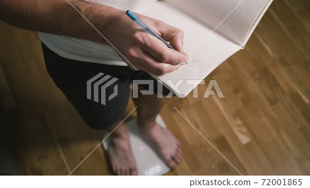 Close-up of slender man bare legs take step on white bathroom scale. The male checks his weight after training at home. Man registers weight and fat percentage on digital weight, healthy lifestyle 72001865
