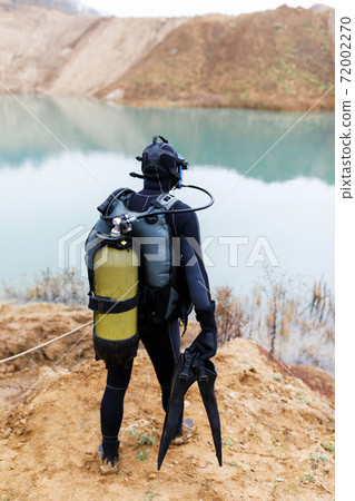 A lifeguard in a wetsuit is preparing to dive into the pond. Search at the bottom of the pond. A lifeguard in a wetsuit is preparing to dive into the pond. Search at the bottom of the pond. 72002270