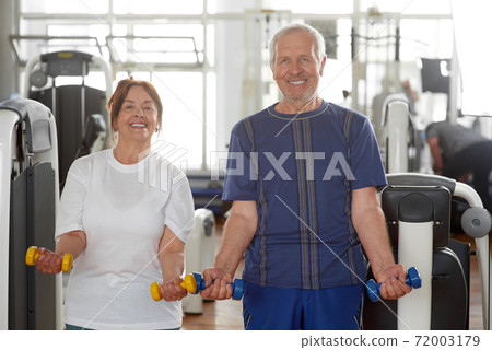 Couple of seniors with dumbbells at gym. 72003179