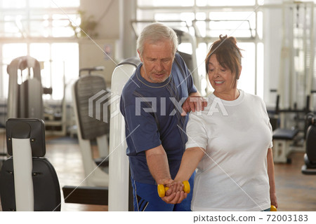 Senior woman lifting dumbbell at gym 72003183