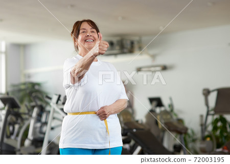 Senior woman measuring her waist at gym. 72003195
