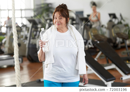 Pretty senior woman with a bottle of water in gym. Pretty senior woman with a bottle of water in gym. 72003196