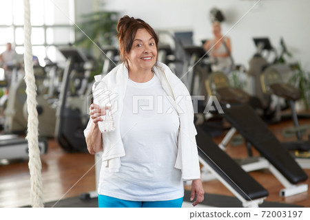 Senior woman holding bottle of water at gym. Senior woman holding bottle of water at gym. 72003197