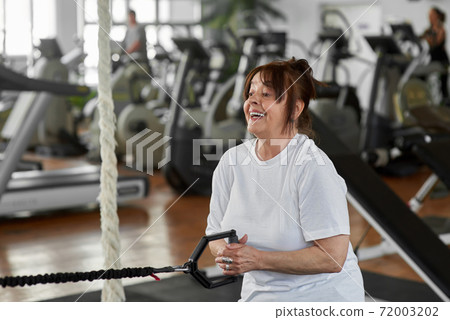 Woman training arms with fitness straps. Woman training arms with fitness straps. 72003202