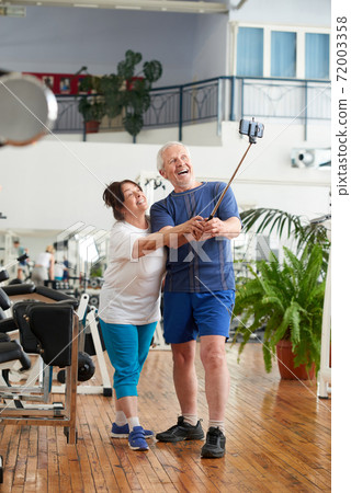 Cheerful senior couple using monopod at gym. Cheerful senior couple using monopod at gym. 72003358