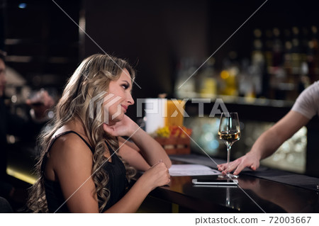 cute blonde girl ordered wine from the bartender in a nightclub cute blonde girl ordered wine from the bartender in a nightclub 72003667