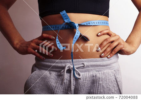 woman measuring waist with tape on knot, african tan isolated 72004088