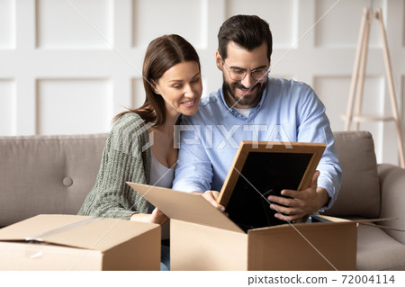 Happy couple renters unpack boxes relocating to new home Happy couple renters unpack boxes relocating to new home 72004114