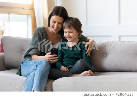 Young mom and small son relax at home with smartphone 72004155