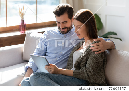 Happy couple relax on sofa using tablet gadget Happy couple relax on sofa using tablet gadget 72004157