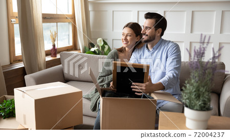 Dreamy couple renters unpack boxes at home visualizing 72004237