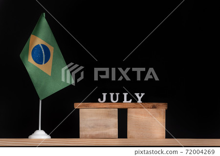 Wooden calendar of July with Brazilian flag on black background. Dates of Brazil in July 72004269