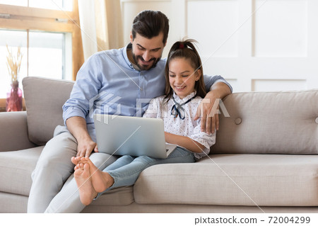 Smiling dad and little daughter using laptop at home 72004299