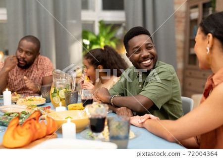 Happy young African man looking at his sister or girlfriend and talking to her Happy young African man looking at his sister or girlfriend and talking to her 72004364