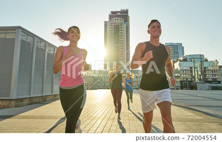 Young mixed race athletes running along city street Young mixed race athletes running along city street 72004554