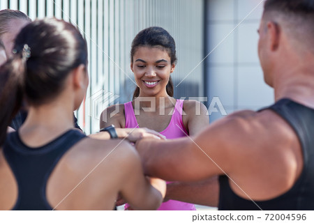 Young mixed race girl stacking hands with team members Young mixed race girl stacking hands with team members 72004596