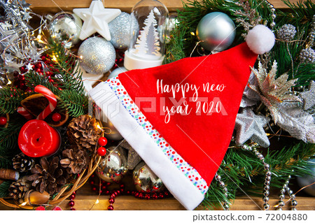 Christmas background. Beautiful card with a red hat. Lettering Happy New Year 2020 Christmas background. Beautiful card with a red hat. Lettering Happy New Year 2020 72004880