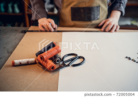 In a family shoe shop a young apprentice works with paper to create a pattern for shoes In a family shoe shop a young apprentice works with paper to create a pattern for shoes 72005004