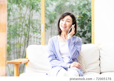 中部女人，在客廳裡用智能手機打電話 72005178