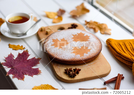 Beautiful fresh sweet pumpkin cake with a maple leaf pattern on a white wooden background 72005212