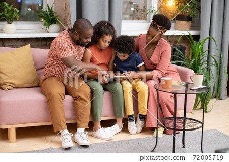 Young African family of father, mother, son and daughter watching movie at home 72005719
