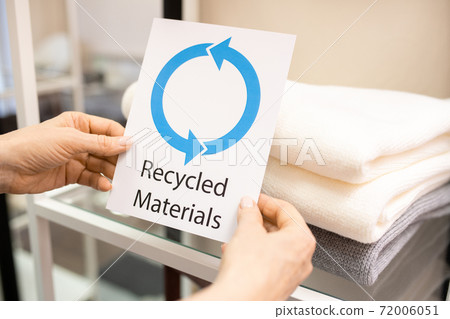 Hands of female shop assistant holding card saying about recycled materials 72006051