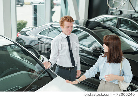 Elegant brunette female consumer in casualwear listening to young sales manager Elegant brunette female consumer in casualwear listening to young sales manager 72006240