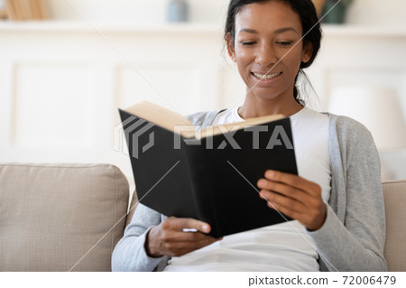 Happy African American female reading book at home Happy African American female reading book at home 72006479