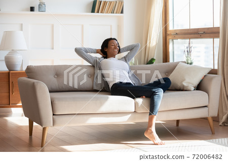 Young biracial woman relax on couch at home dreaming Young biracial woman relax on couch at home dreaming 72006482