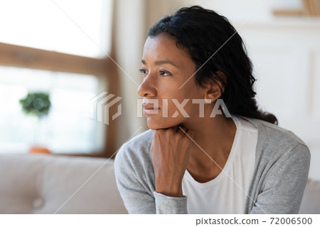 Pensive African American woman look in distance dreaming 72006500