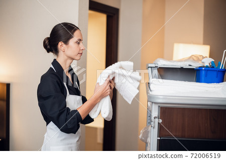 A young happy uniformed maid carrying towels A young happy uniformed maid carrying towels 72006519