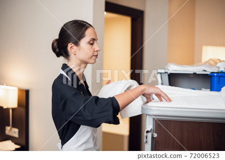 A young uniformed maid getting some fresh towels A young uniformed maid getting some fresh towels 72006523