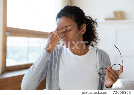 Tired biracial woman take off glasses suffer from migraine 72006566