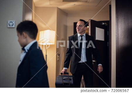 Father and son in formal wear entering a hotel room, the father 72006567
