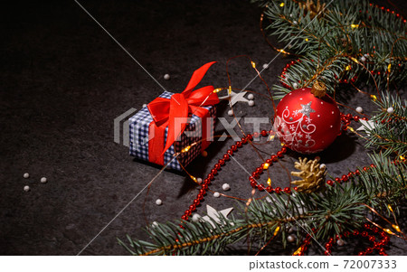 Background or preparation for a postcard. Christmas tree branches and decorations on a dark background. A Christmas present. Background or preparation for a postcard. Christmas tree branches and decorations on a dark background. A Christmas present. 72007333