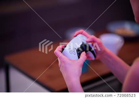 Girl with next gen controller in her hands playing games at home. 72008523