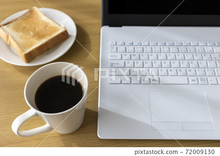 Image of using a laptop while eating breakfast 72009130