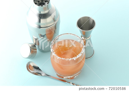 Pink salty dog with salt on the edge of the glass, cocktail shaker and major cup Pink salty dog with salt on the edge of the glass, cocktail shaker and major cup 72010586