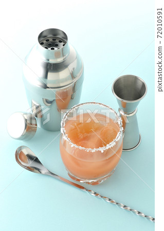 Pink salty dog with salt on the edge of the glass, cocktail shaker and major cup Pink salty dog with salt on the edge of the glass, cocktail shaker and major cup 72010591