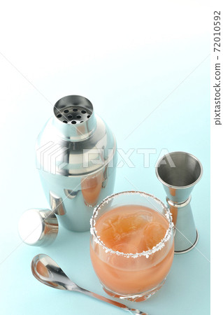 Pink salty dog with salt on the edge of the glass, cocktail shaker and major cup 72010592