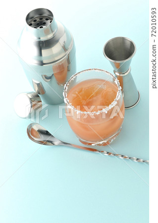 Pink salty dog with salt on the edge of the glass, cocktail shaker and major cup Pink salty dog with salt on the edge of the glass, cocktail shaker and major cup 72010593