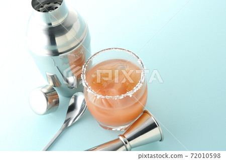 Pink salty dog with salt on the edge of the glass, cocktail shaker and major cup Pink salty dog with salt on the edge of the glass, cocktail shaker and major cup 72010598