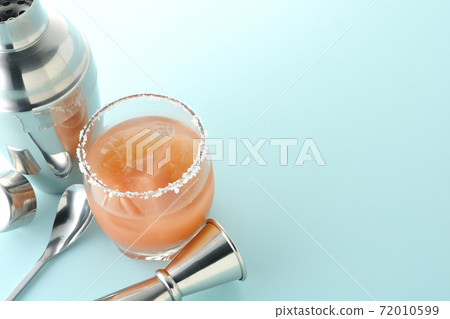 Pink salty dog with salt on the edge of the glass, cocktail shaker and major cup Pink salty dog with salt on the edge of the glass, cocktail shaker and major cup 72010599