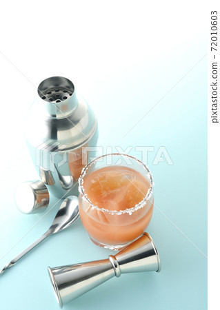 Pink salty dog with salt on the edge of the glass, cocktail shaker and major cup 72010603